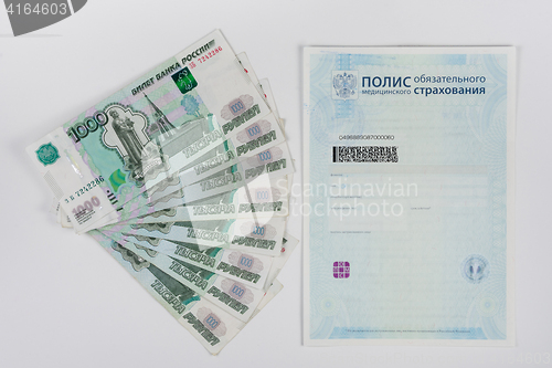 Image of Next to the health insurance policy is a fan of thousand-pack of banknotes, white background