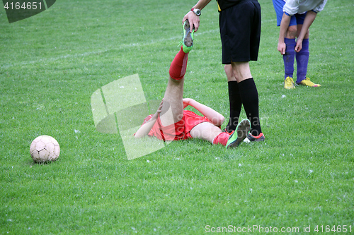 Image of Referee provides assistance injured player at the football match