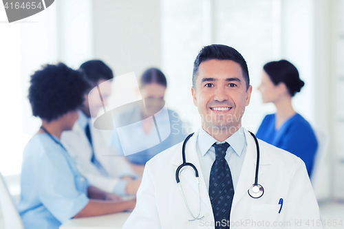 Image of happy doctor over group of medics at hospital