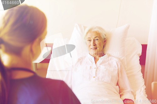 Image of doctor or nurse visiting senior woman at hospital