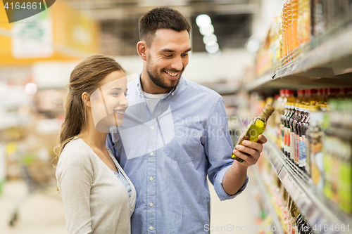 Image of happy couple buying olive oil at grocery store