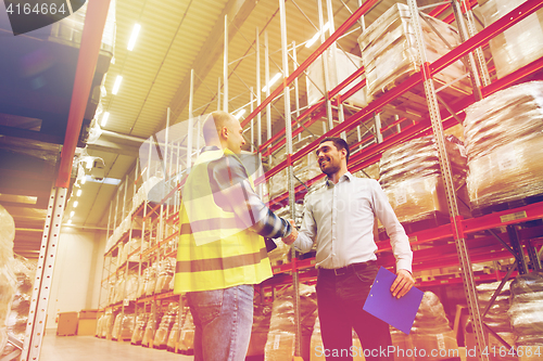 Image of worker and businessmen with clipboard at warehouse