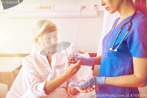 Image of nurse giving medicine to senior woman at hospital