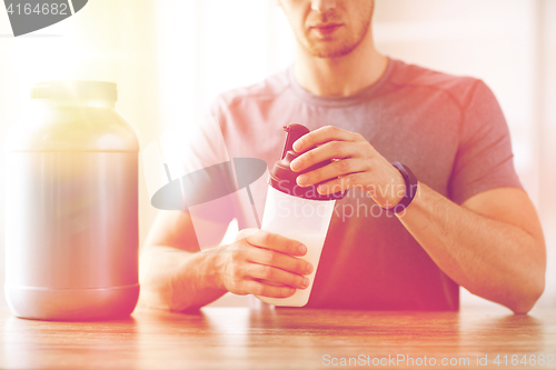 Image of close up of man with protein shake bottle and jar