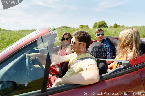 Image of happy friends driving in cabriolet car and talking