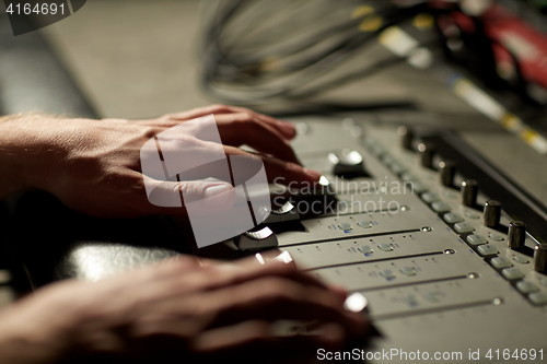 Image of hands on mixing console in music recording studio