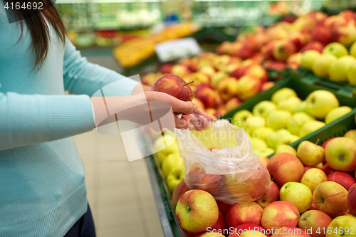 Image of woman with bag buying apples at grocery store