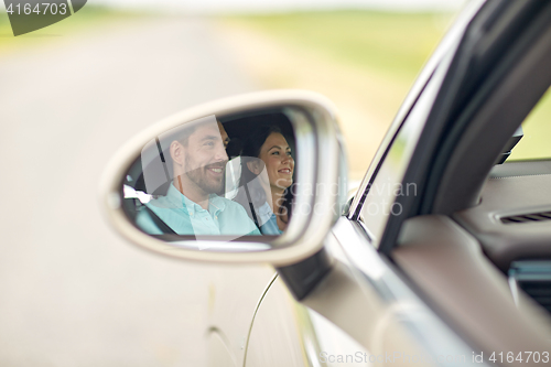 Image of side mirror reflection of happy couple driving car