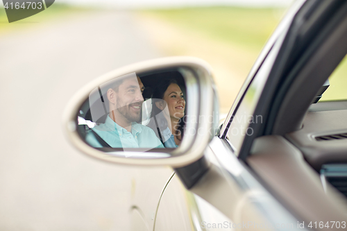 Image of side mirror reflection of happy couple driving car