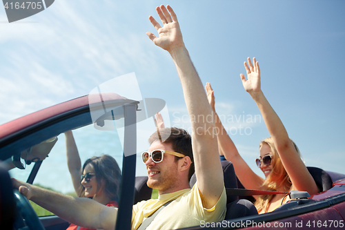 Image of happy friends driving in cabriolet car at country