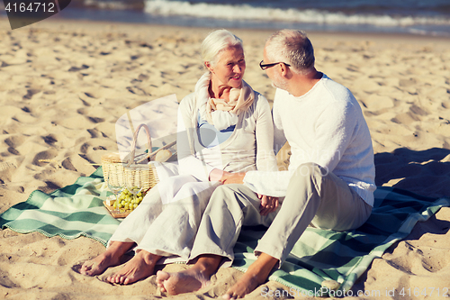 Image of happy senior couple having picnic on summer beach