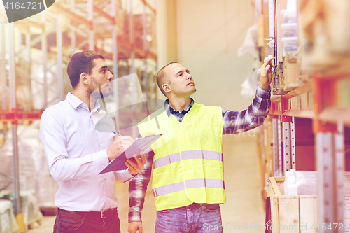 Image of worker and businessmen with clipboard at warehouse