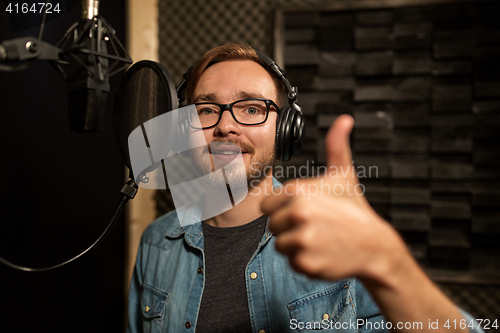 Image of man with headphones singing at recording studio