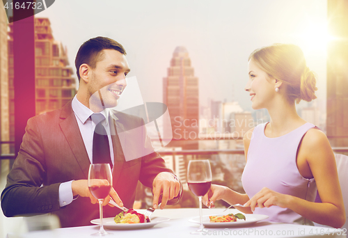 Image of smiling couple eating main course at restaurant