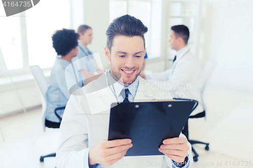 Image of happy doctor with tablet pc over team at clinic