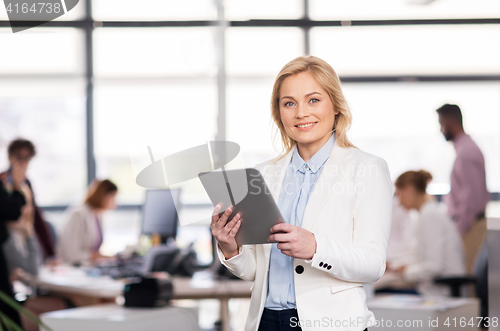 Image of smiling businesswoman with tablet pc at office