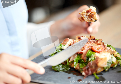 Image of woman eating prosciutto ham salad at restaurant