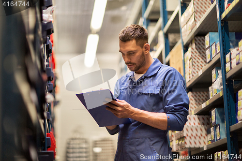 Image of auto mechanic with clipboard at car workshop