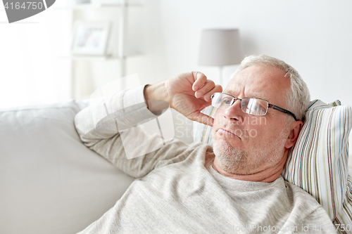 Image of close up of senior man in glasses thinking at home