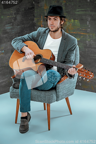 Image of Cool guy with hat playing guitar on gray background