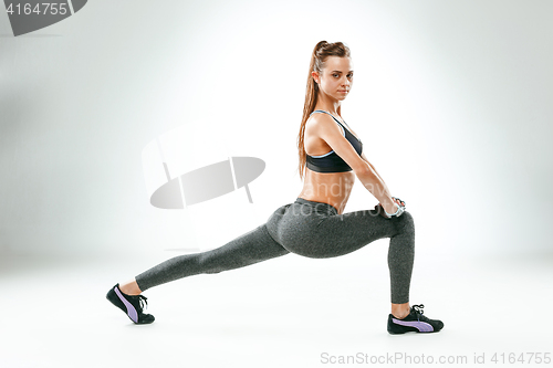 Image of Beautiful slim brunette doing some stretching exercises in a gym