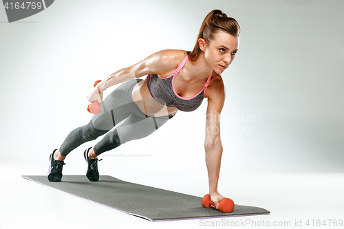 Image of Beautiful slim brunette doing some stretching exercises