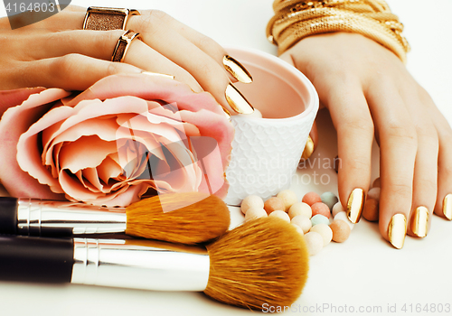 Image of woman hands with golden manicure and many rings holding brushes,