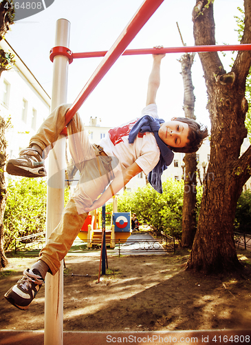 Image of little cute blond boy hanging on playground outside, alone train