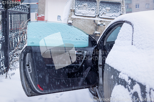 Image of Opened car door and snowfall in city