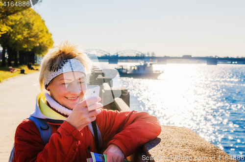 Image of A woman photographs the phone. Embankment in Riga