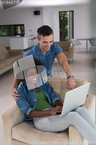 Image of multiethnic couple on an armchair with a laptop