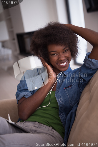 Image of African american woman at home in chair with tablet and head pho