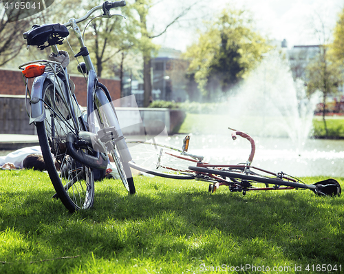 Image of lifestyle people concept: couple of bicycle on green grass in summer park at fountain