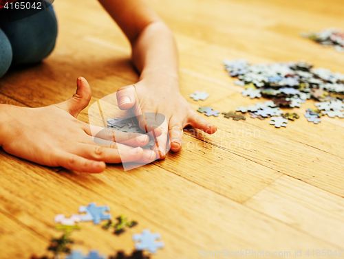 Image of little kid playing with puzzles on wooden floor together with pa