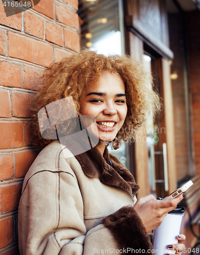 Image of young pretty african american women drinking coffee outside in c