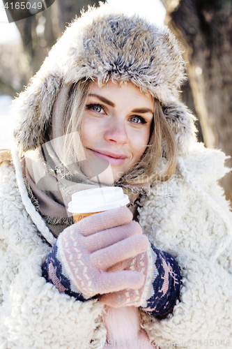 Image of young pretty teenage hipster girl outdoor in winter snow park having fun drinking coffee, warming up happy smiling, lifestyle people concept