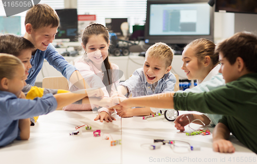 Image of happy children making fist bump at robotics school