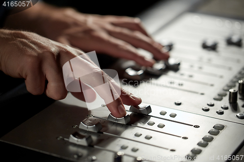 Image of hands on mixing console in music recording studio