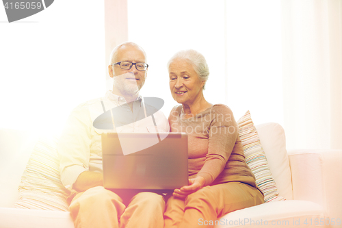 Image of happy senior couple with laptop at home