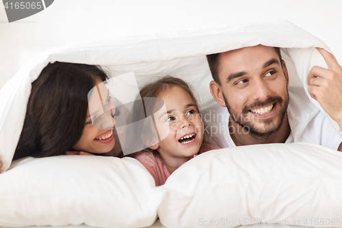 Image of happy family lying in bed under blanket at home