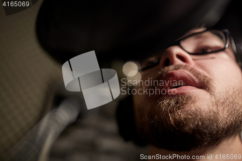 Image of man with headphones singing at recording studio