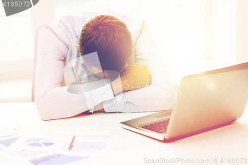 Image of businessman with laptop and papers in office