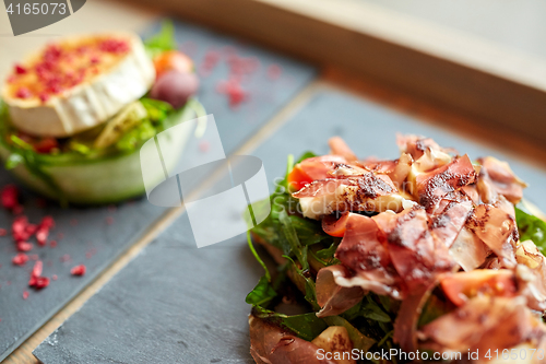 Image of prosciutto ham salad on stone plate at restaurant