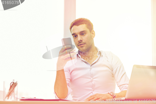 Image of businessman with smartphone and laptop at office