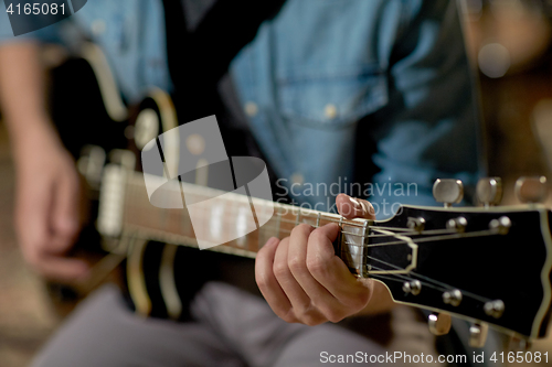 Image of close up of man playing guitar at studio rehearsal