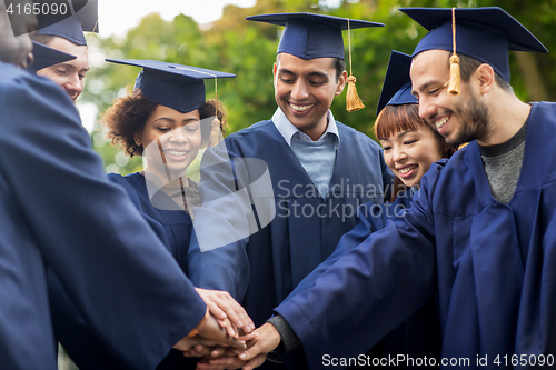 Image of happy students in mortar boards with hands on top