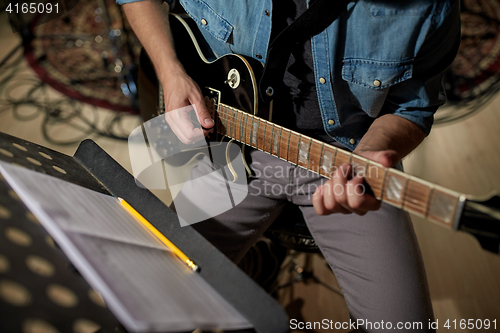 Image of man with music book on stand playing guitar