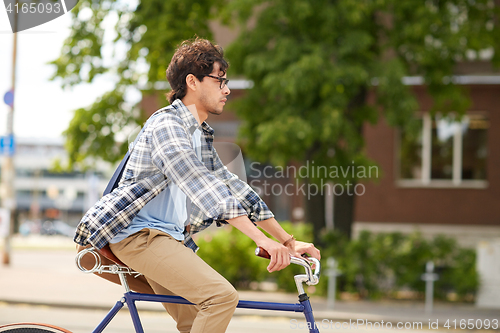 Image of young hipster man with bag riding fixed gear bike