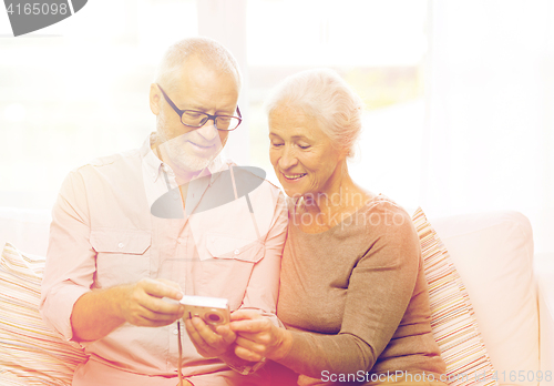Image of happy senior couple with camera at home