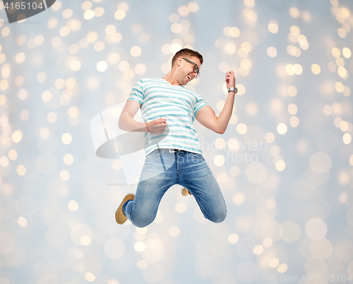 Image of happy man jumping and playing imaginary guitar